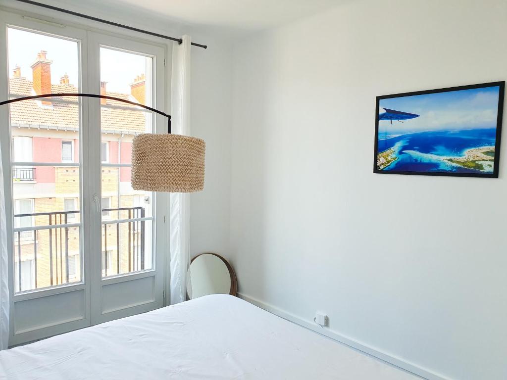 ein weißes Schlafzimmer mit einem Fenster und einem Bett in der Unterkunft EXIGEHOME-Appart très lumineux aux portes de Paris in Suresnes