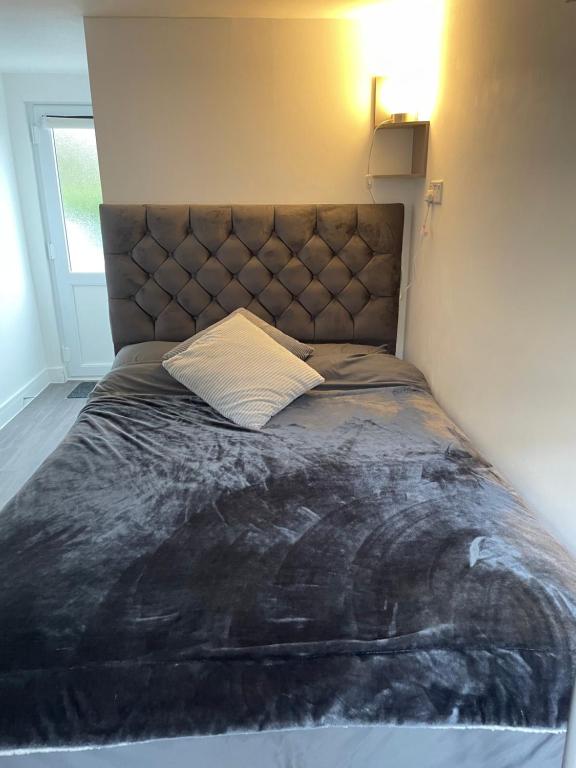 a large bed in a bedroom with a large headboard at Private en-suite garden room in Countess Wear