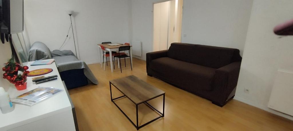 ein Wohnzimmer mit einem Sofa und einem Tisch in der Unterkunft Pantin appartement en rez-de-chaussée in Pantin