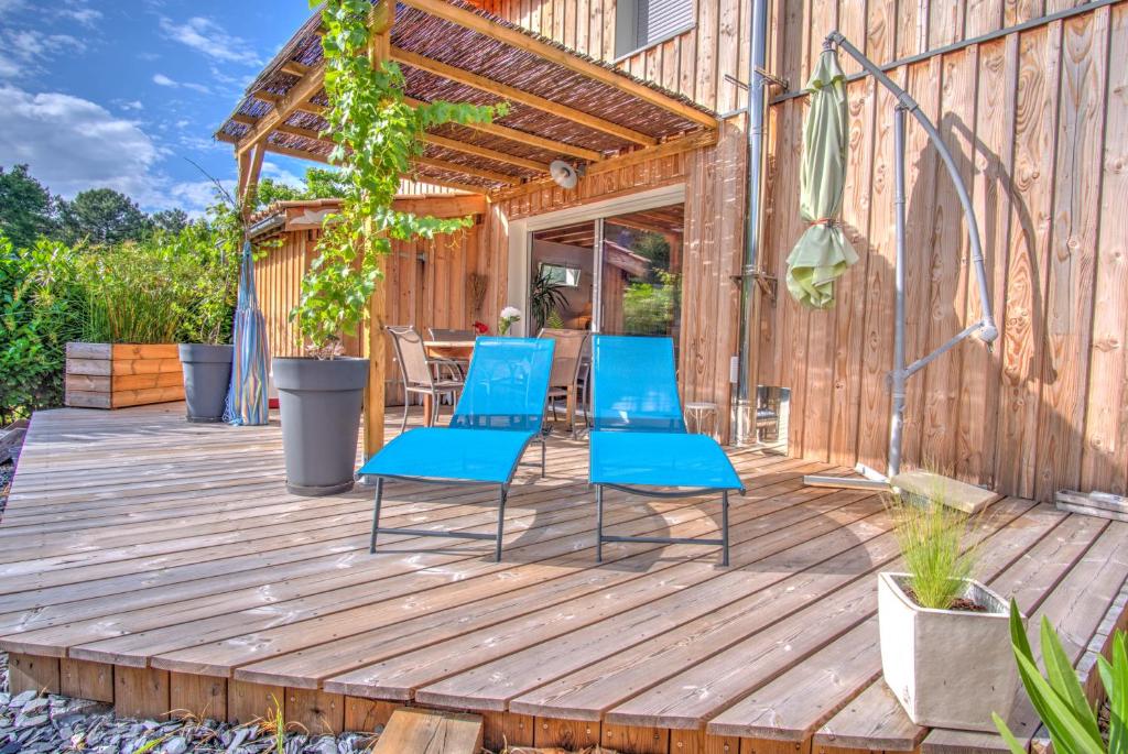2 chaises bleues assises sur une terrasse en bois dans l'établissement Gite de charme Bassin d'Arcachon- Piscine-Proche des plages-Au calme, à Gujan-Mestras