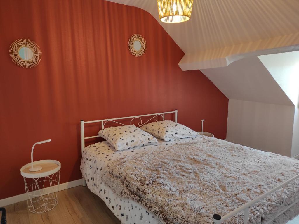 a bedroom with a bed and a red wall at la maison du bonheur in Alençon