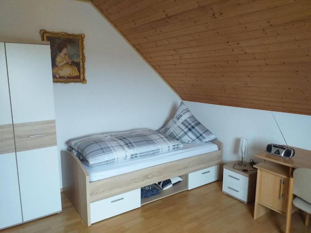 Dormitorio pequeño con cama en el ático en Ferienwohnung 'am Bienwald', en Schaidt