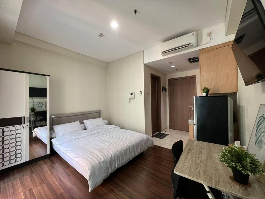 Schlafzimmer mit einem Bett, einem Tisch und einem Spiegel in der Unterkunft West Jakarta Gem Modern Studio at Puri Orchard in Jakarta