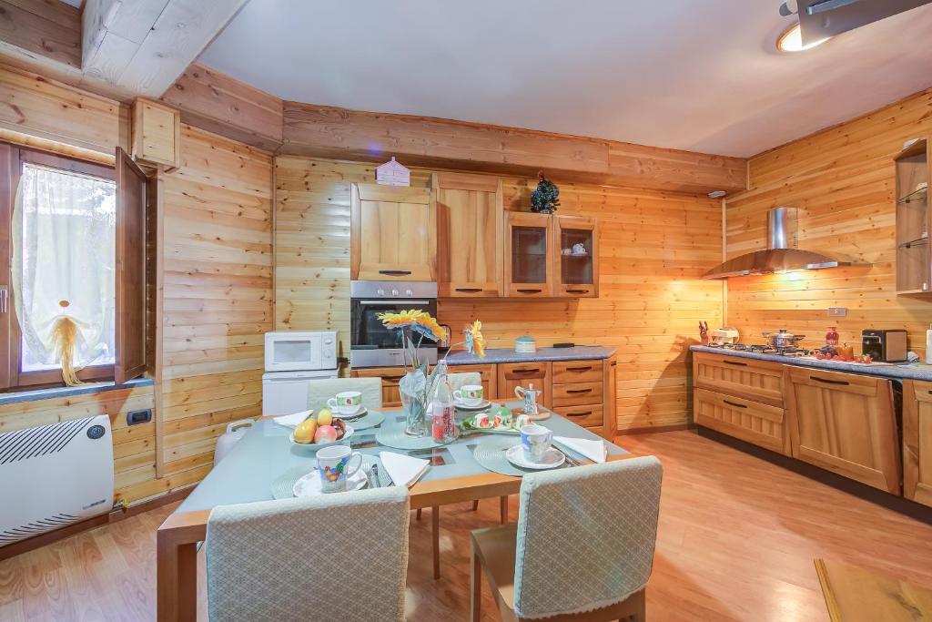 - une cuisine avec des murs en bois, une table et des chaises dans l'établissement Studio Borgata Ski In Ski Out 300m - Happy Rentals, à Sestrières