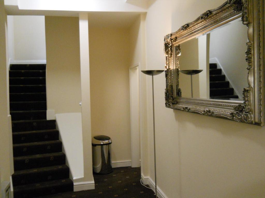 a mirror on a wall next to a staircase at Citystay Guest House in London