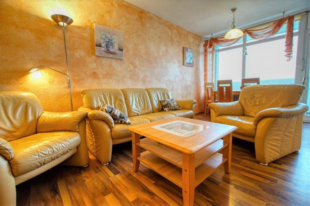 ein Wohnzimmer mit Ledersofas und einem Couchtisch in der Unterkunft Ferienpark - Haus H, App 0H0709 in Heiligenhafen