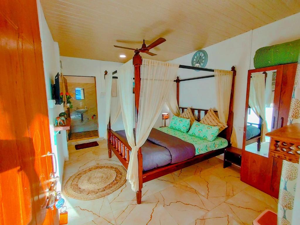 1 dormitorio con cama con dosel y espejo en EcoZen Holiday Rooms, en Agonda