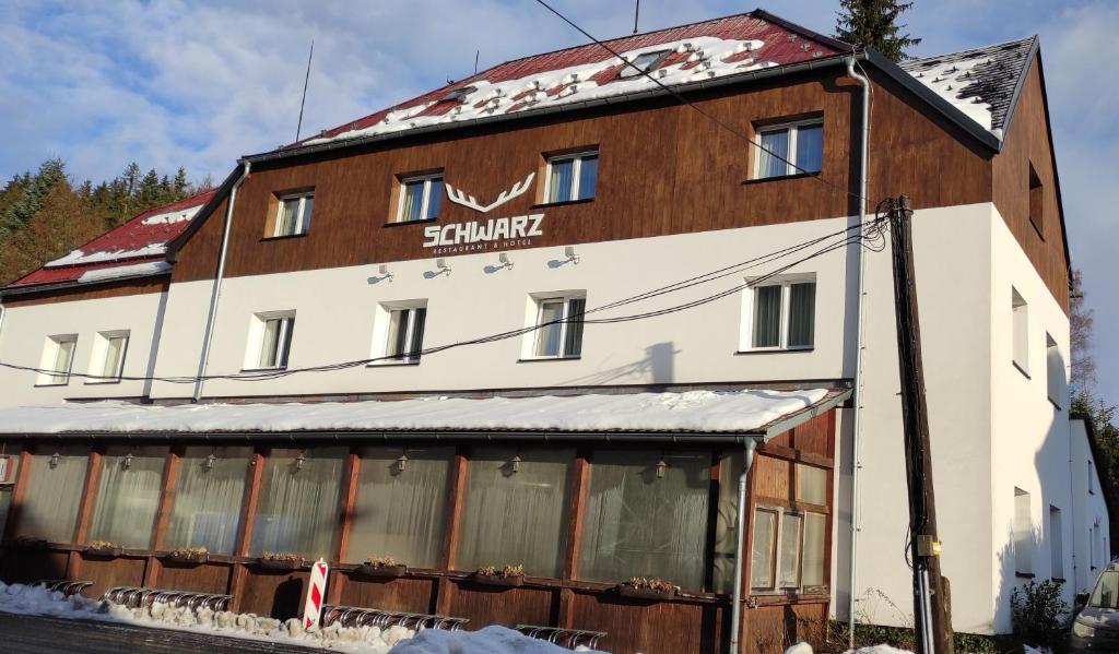 a building with a sign on the side of it at Hotel Schwarz in Nové Hamry