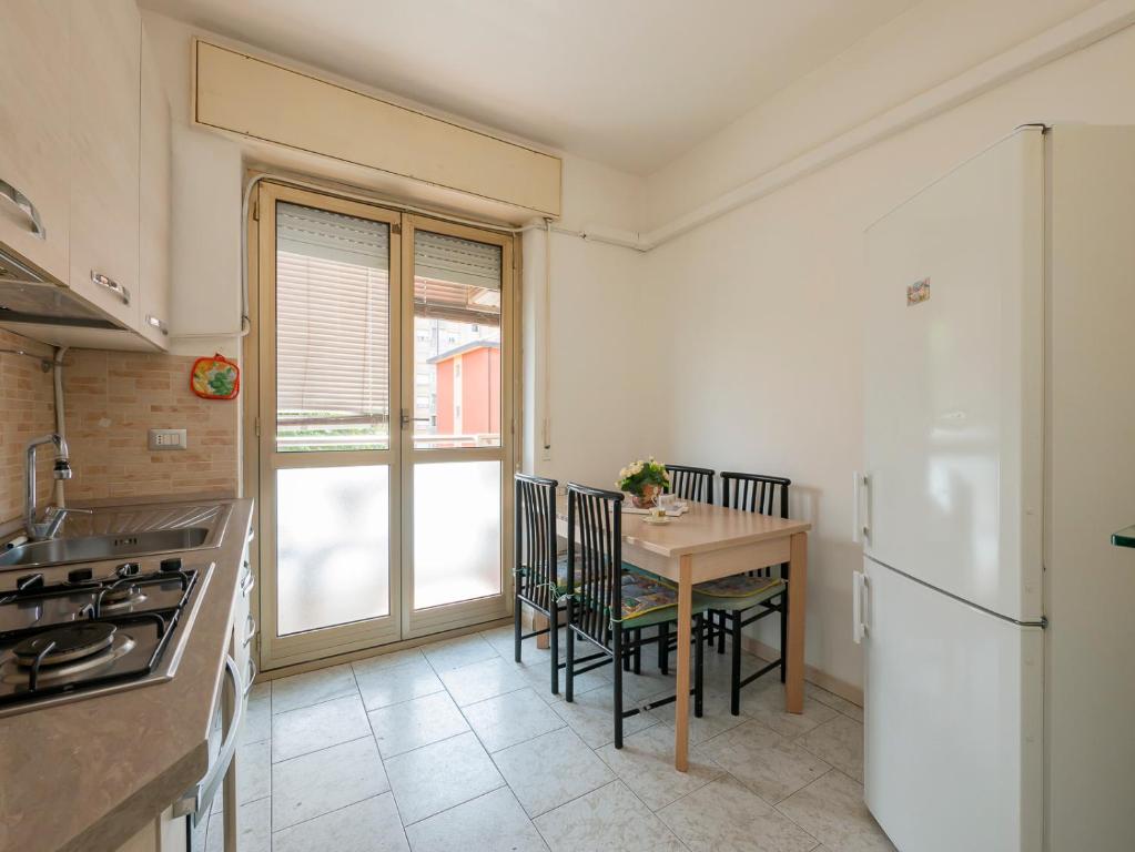 Ampio e luminoso appartamento, posto auto gratuito - Quarenghi في ميلانو: مطبخ مع طاولة وثلاجة بيضاء
