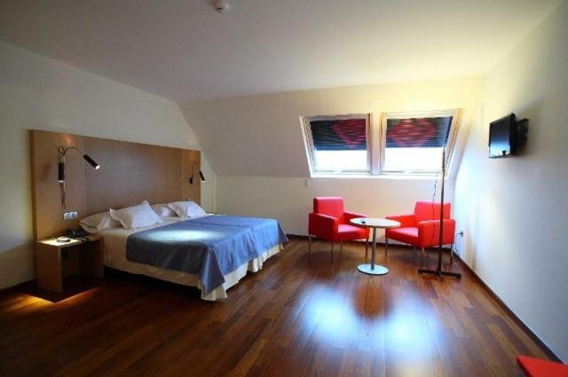 um quarto com uma cama e 2 cadeiras vermelhas em Hotel Ril em Burela de Cabo