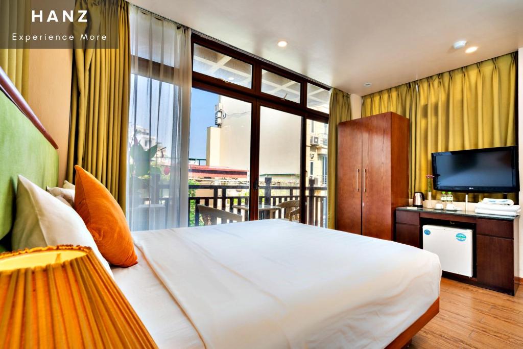a bedroom with a large bed and a television at HANZ Artisan Lakeview Hotel Hanoi in Hanoi