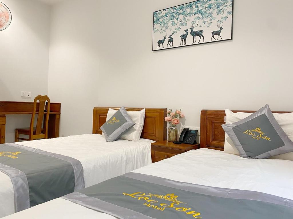 a room with two beds and a picture on the wall at Lộc Sơn Hotel in Buon Ma Thuot