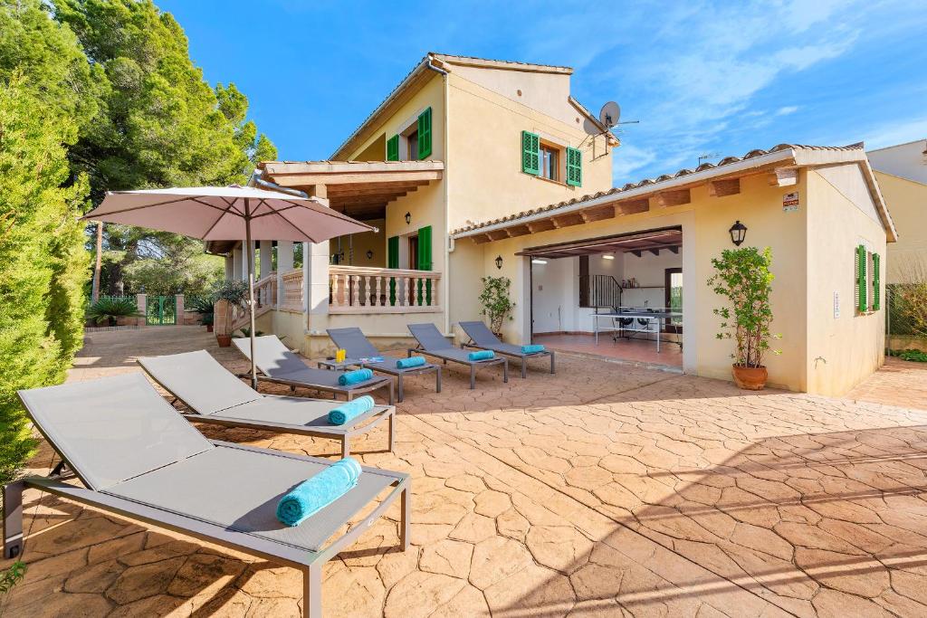 a group of lounge chairs and an umbrella in front of a house at Villa Manresa in Alcudia by JS Villas in Alcudia