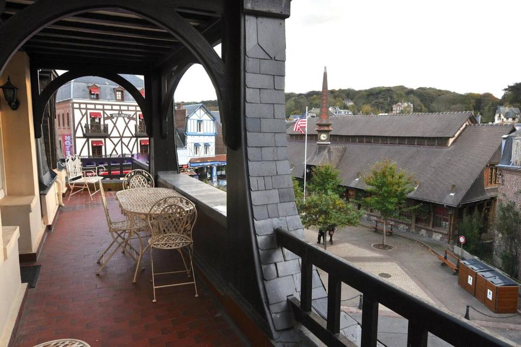 un balcon avec tables et chaises et vue sur la ville dans l'établissement La terrasse, à Étretat