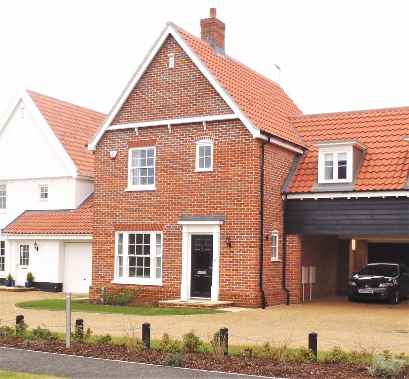 a brick house with a car parked in the driveway at Jubilee View in Southwold