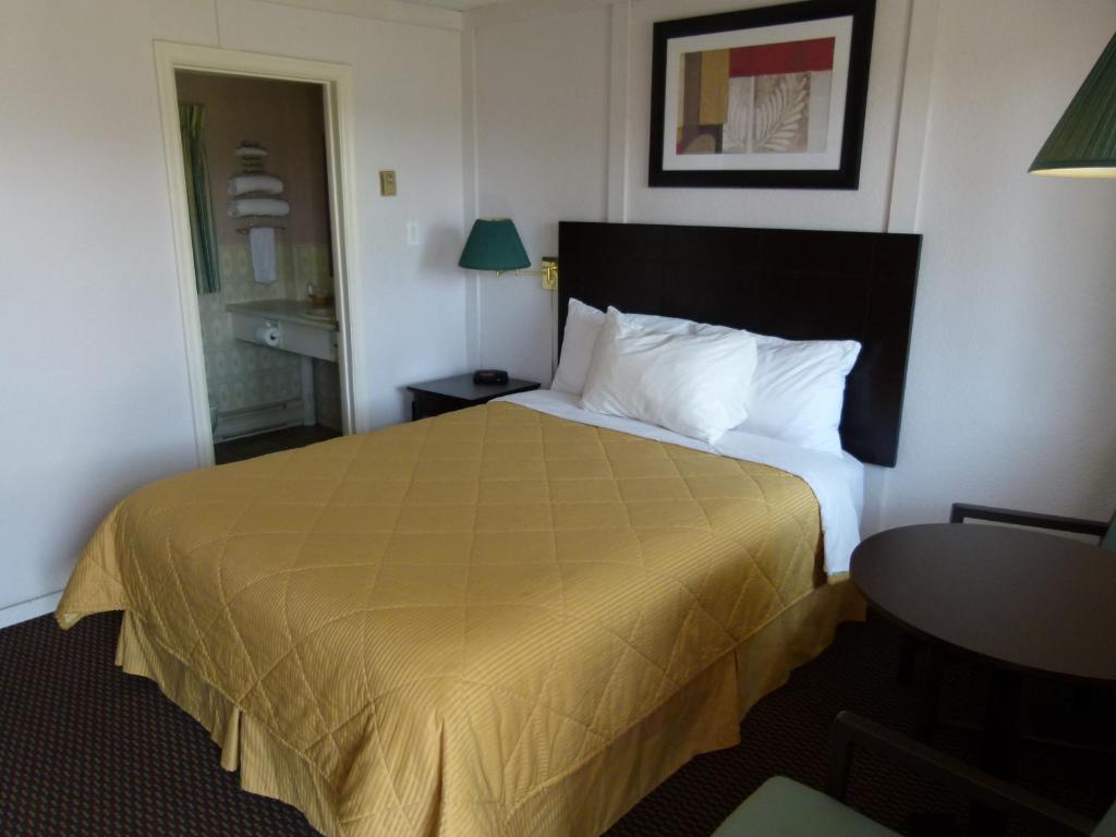 a hotel room with a bed with a yellow bedspread at Country Squire Motel in Arnprior