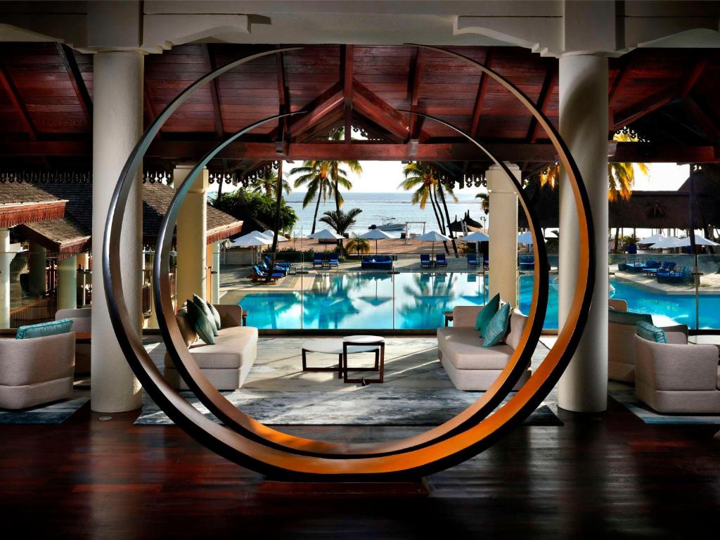a hotel lobby with a pool with chairs and a table at Sofitel Mauritius L'Imperial Resort & Spa in Flic-en-Flac