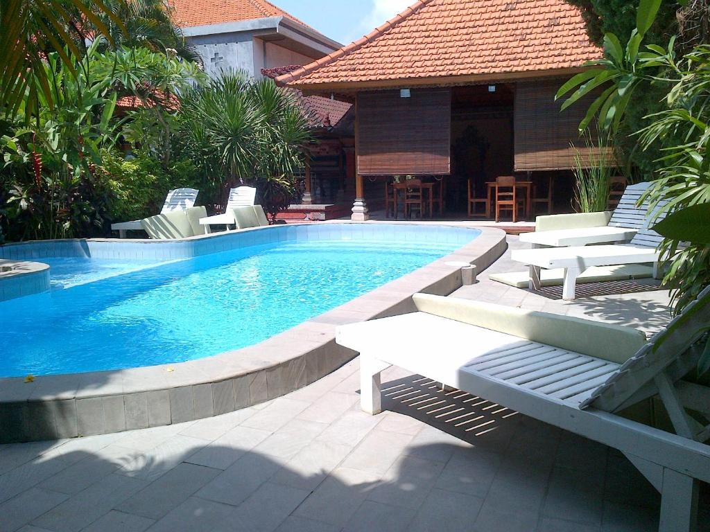 a swimming pool with chaise lounges and chairs around it at Adus Beach Inn in Legian