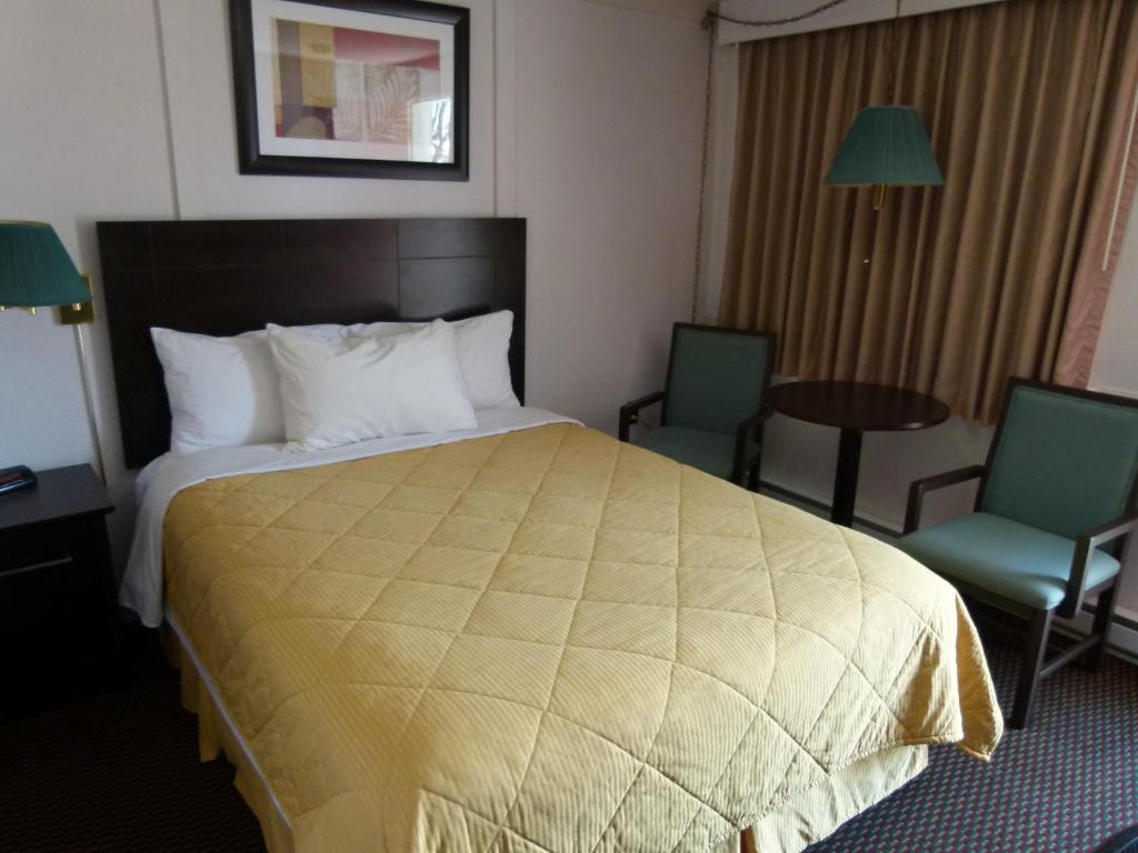 a hotel room with a large bed and two chairs at Country Squire Motel in Arnprior