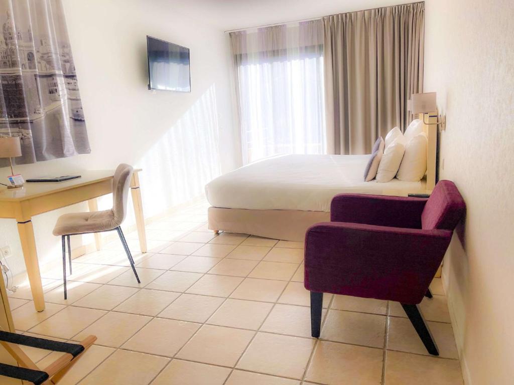 Pokój hotelowy z łóżkiem, biurkiem i krzesłem w obiekcie Best Western Gemenos en Provence w mieście Gémenos
