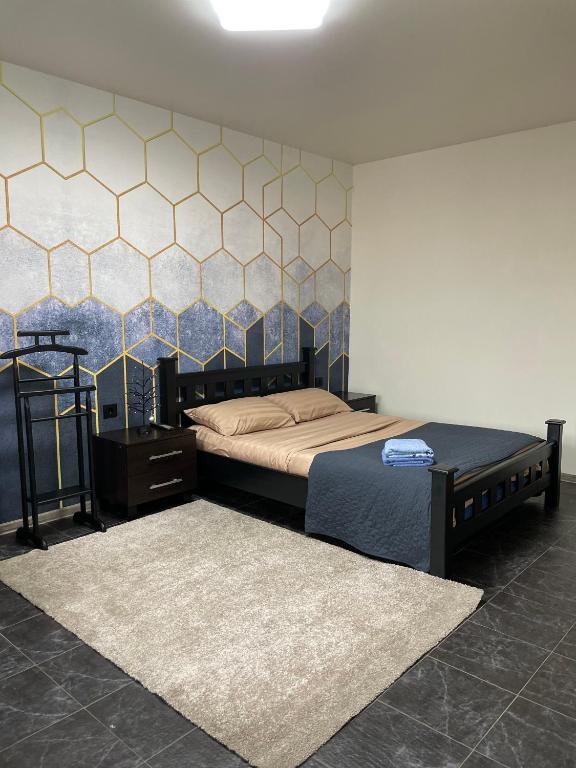 a bedroom with a bed and a tiled wall at Квартира Сапфір Avenue Myru 35a in Chernihiv