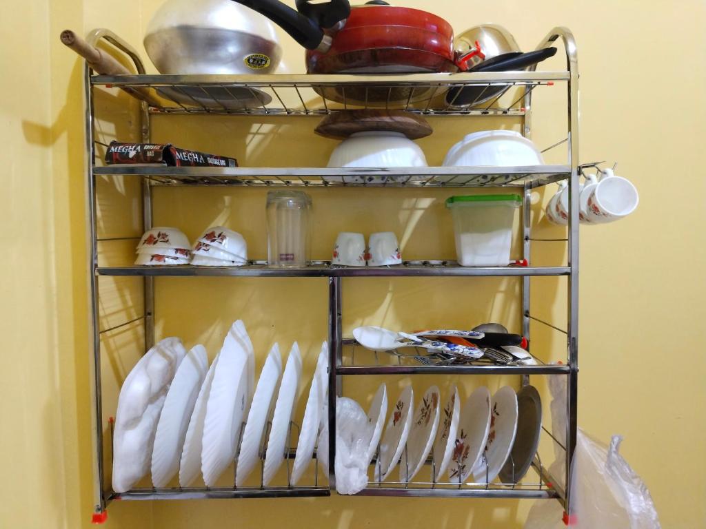 a rack of dishes and utensils in a kitchen at Maya home stay in Kolkata