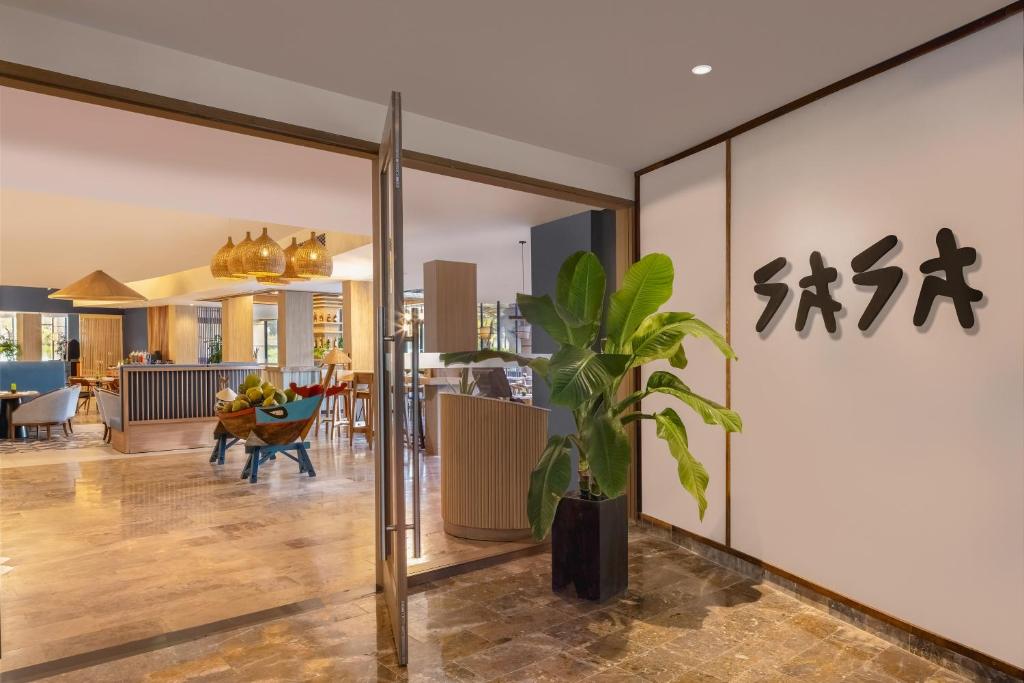 A polished lobby entrance with tropical planting and a glimpse into the lounge.