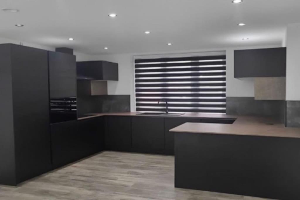 a kitchen with black and white cabinets and a counter at Entire Apartment perfectly located for Heathrow Airport in Uxbridge