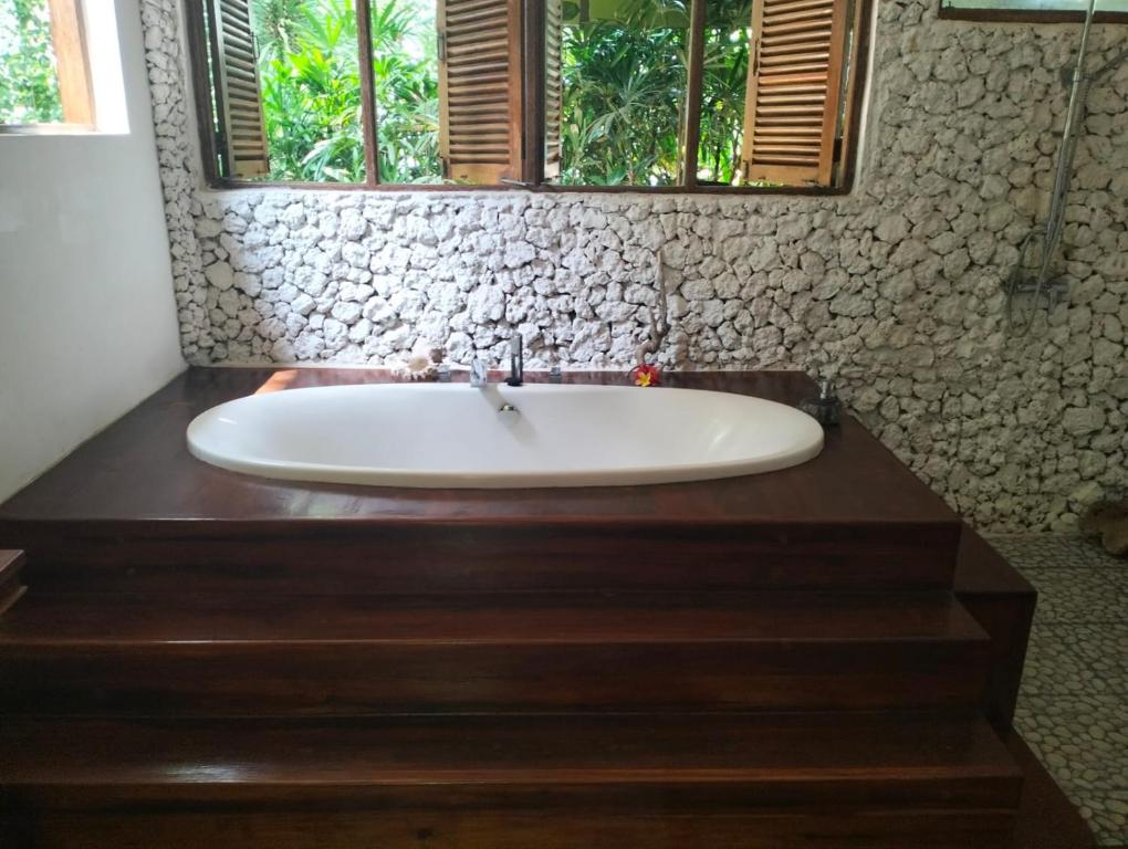 uma banheira branca na casa de banho com uma janela em eco beach house bali em Penginuman