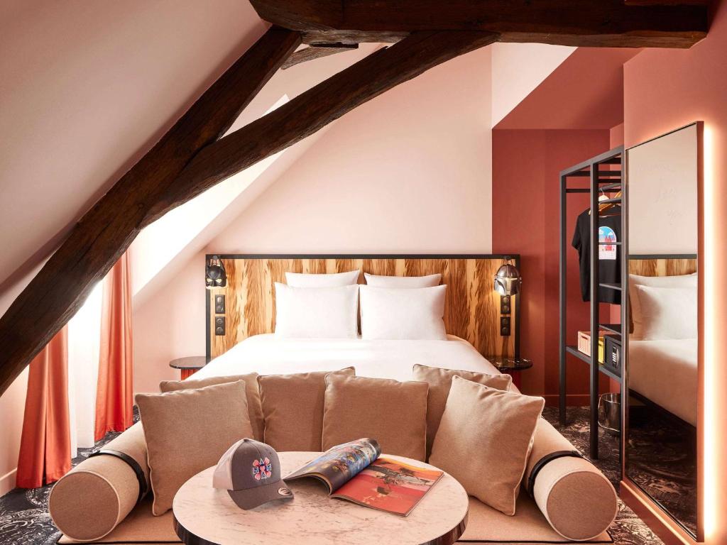 um quarto com uma cama e um sofá com uma mesa em Mama Shelter Rennes em Rennes