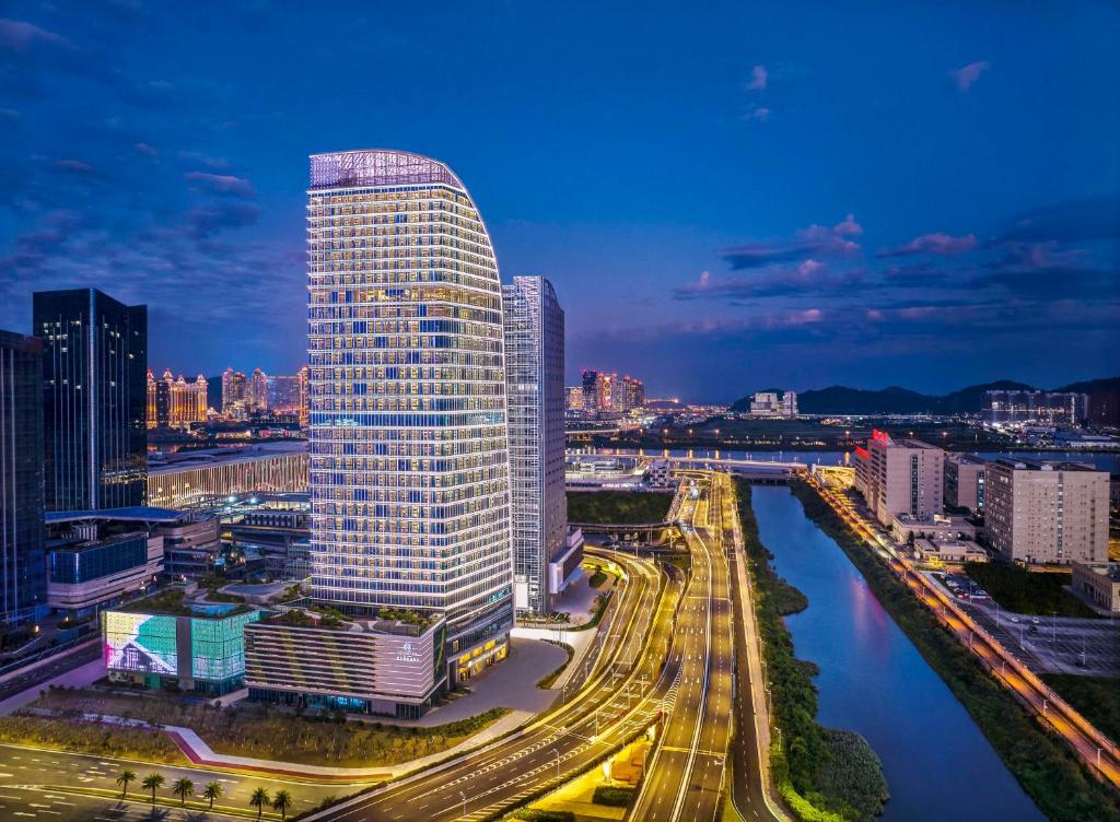 ein hohes Gebäude in einer Stadt neben einem Fluss in der Unterkunft DoubleTree by Hilton Zhuhai Hengqin in Zhuhai