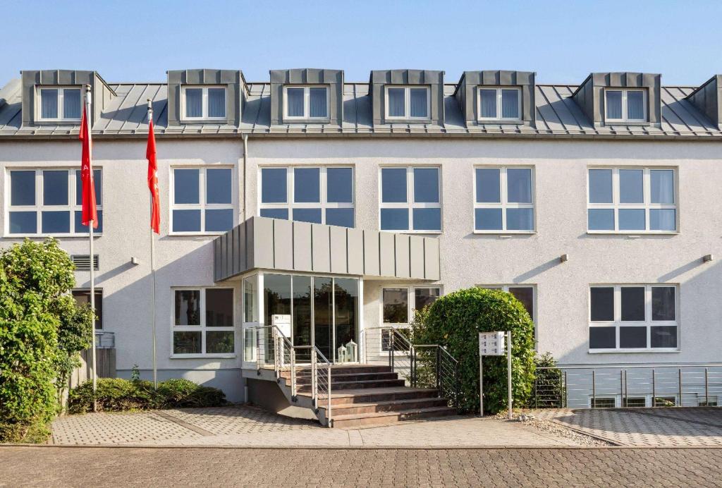 um grande edifício branco com duas bandeiras à frente em Amedia Frankfurt Russelsheim Trademark Collection by Wyndham em Rüsselsheim
