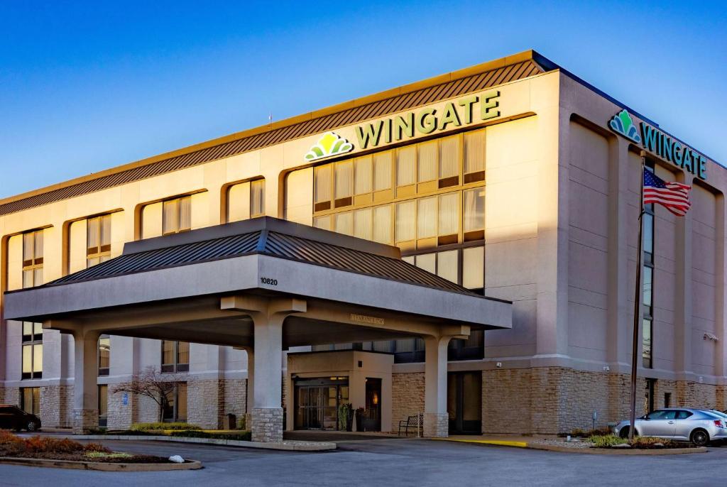 un edificio de oficinas ganador con un coche aparcado delante en Wingate by Wyndham St Louis Airport en Saint Ann
