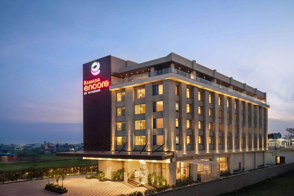 een hotelgebouw met een bord erop bij Ramada Encore by Wyndham Amritsar Airport in Amritsar
