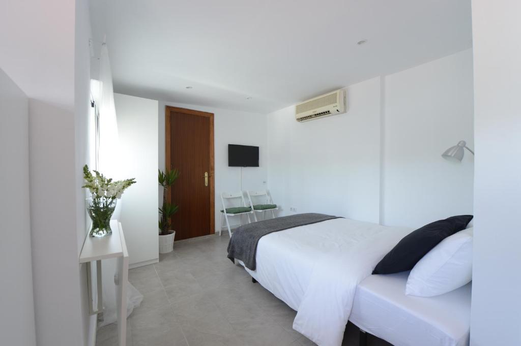 a white bedroom with a bed and a television at Ático, Studio 300 meters from Cathedral and Giralda in Seville