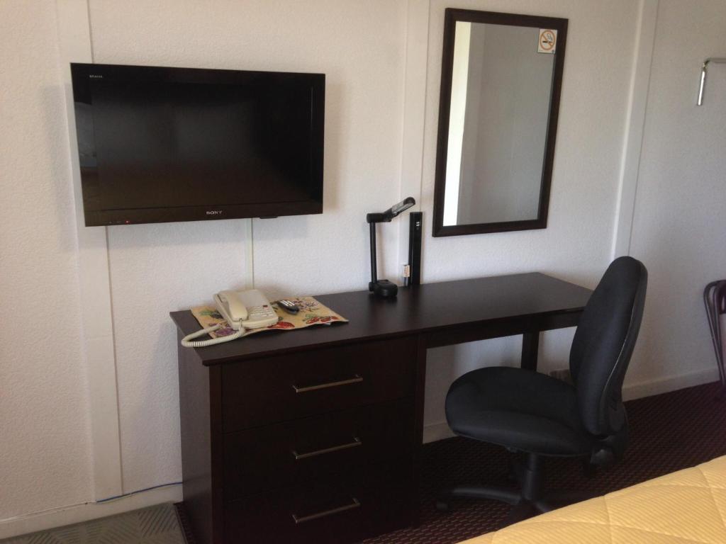 a desk with a television and a chair in a hotel room at Country Squire Motel in Arnprior