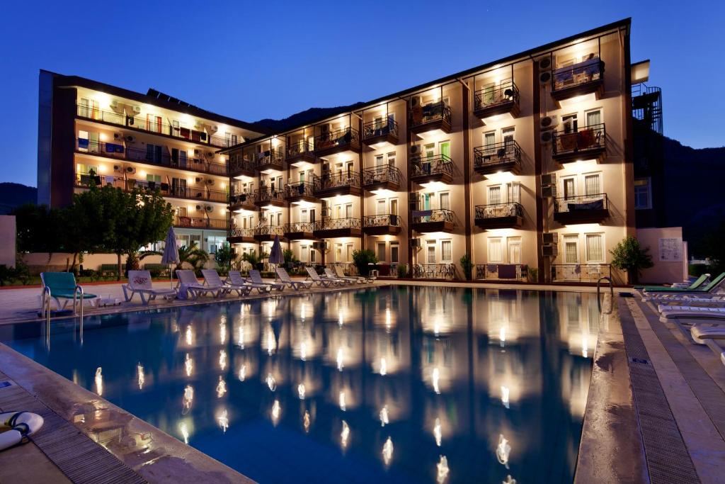 un hotel con piscina frente a un edificio en Garden Park Beldibi Hotel en Beldibi