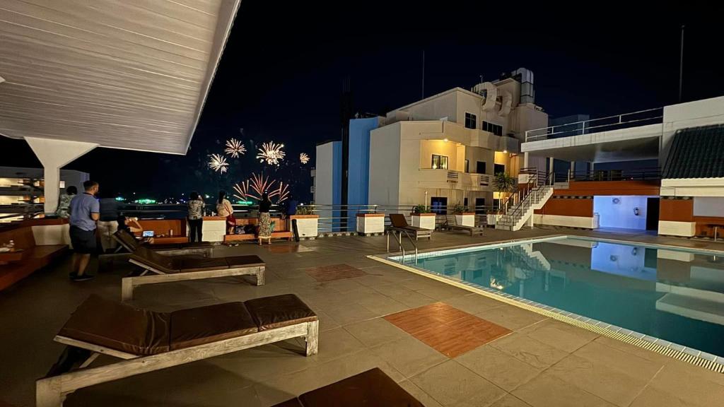芭達雅中心的住宿－Highfive Hotel Pattaya，一位晚上站在游泳池旁的人