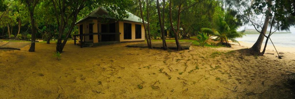 a small house on a sandy beach with trees at Yasawa Long Beach Hideout Resort in Vuake
