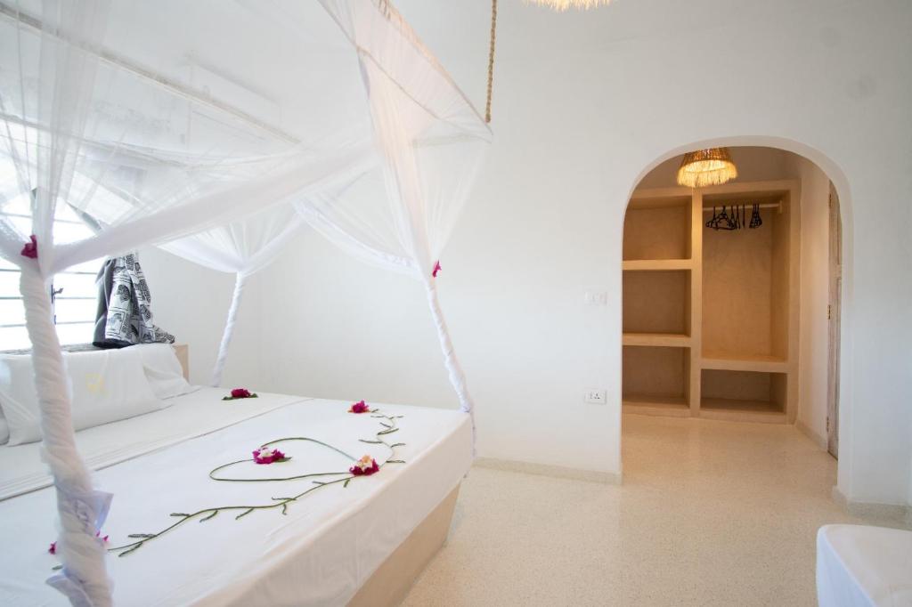 Un dormitorio con una cama blanca con flores. en Weber Zazu - Maisha Resort, en Watamu