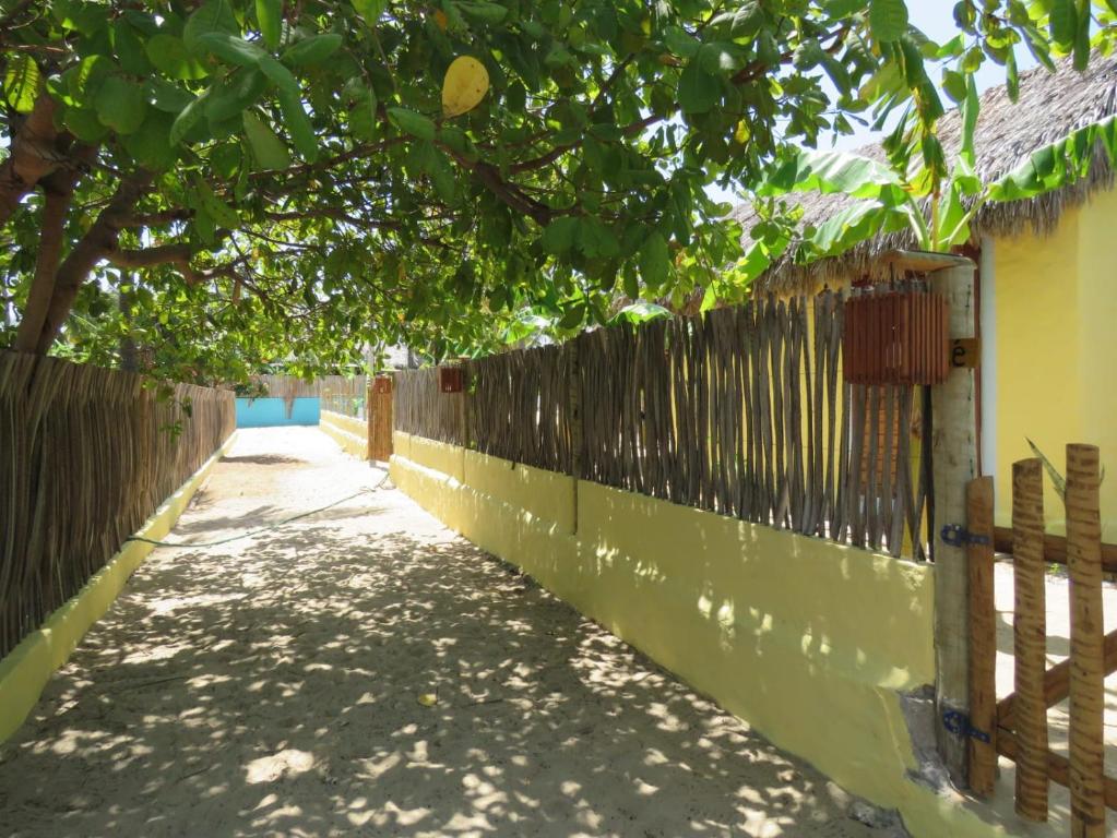 a fence next to a sidewalk next to a tree at Pitico - Pousada Icaraí Kite Village in Icaraí