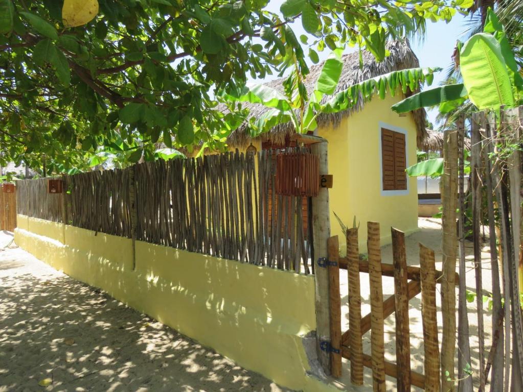 a fence in front of a yellow house at Pitico - Pousada Icaraí Kite Village in Icaraí