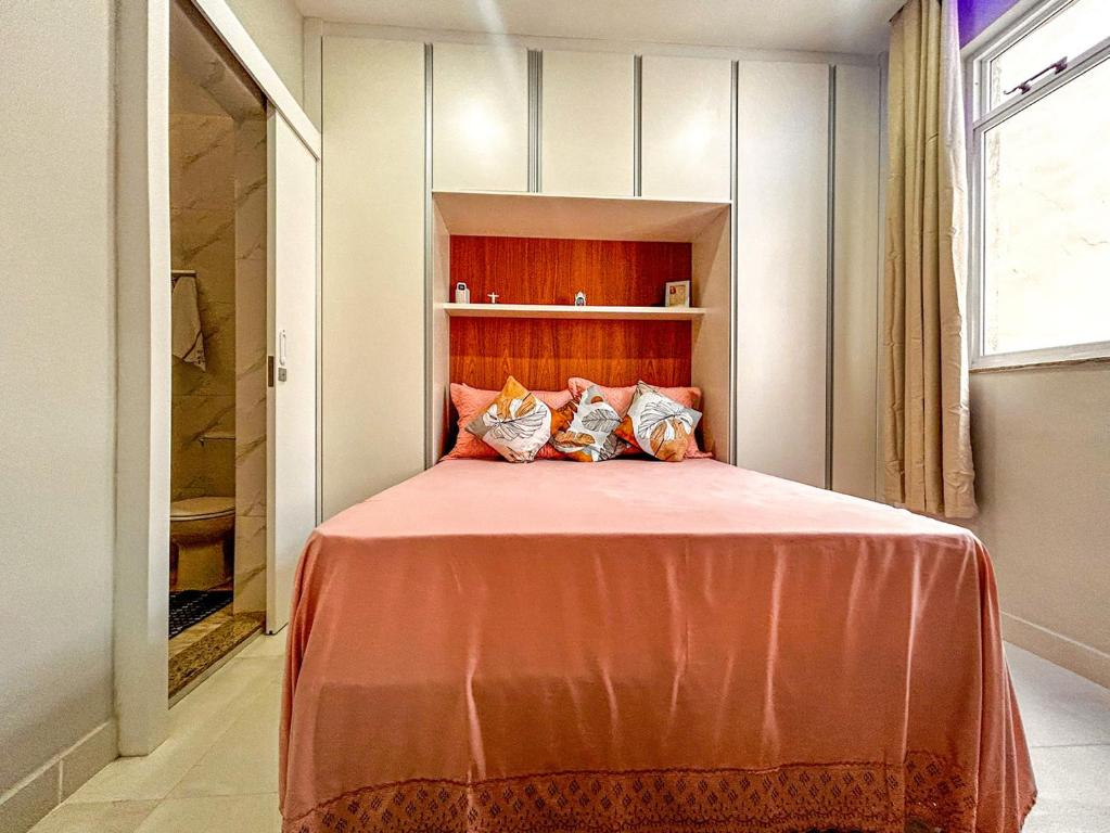 a bedroom with a bed with orange sheets and pillows at Ótimo studio c WiFi a 190m da Praia do Leme - RJ in Rio de Janeiro