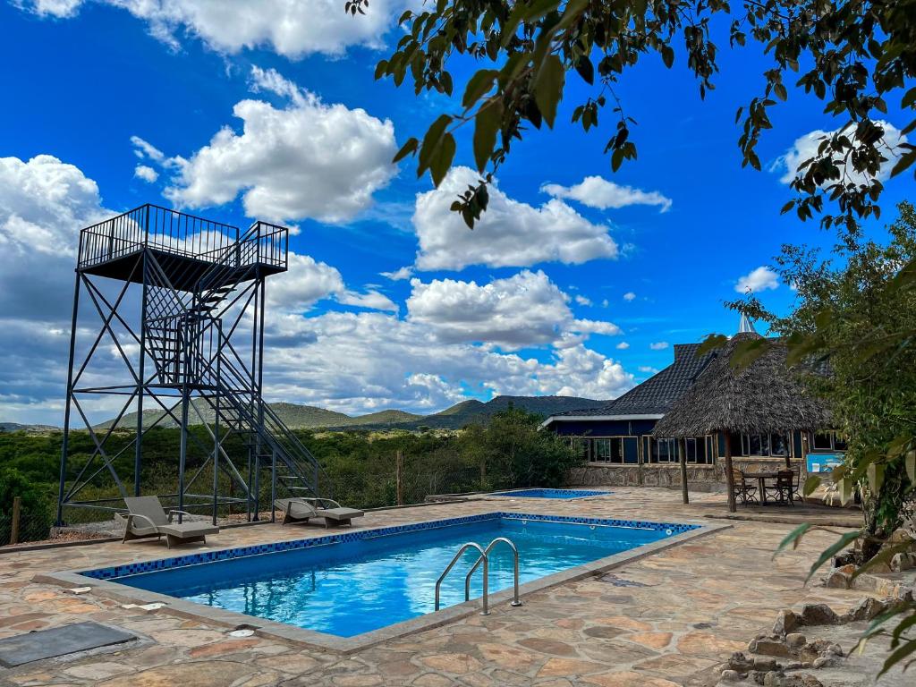 een zwembad met een basketbalring naast een huis bij Orng'atuny Mara King Camp in Masai Mara
