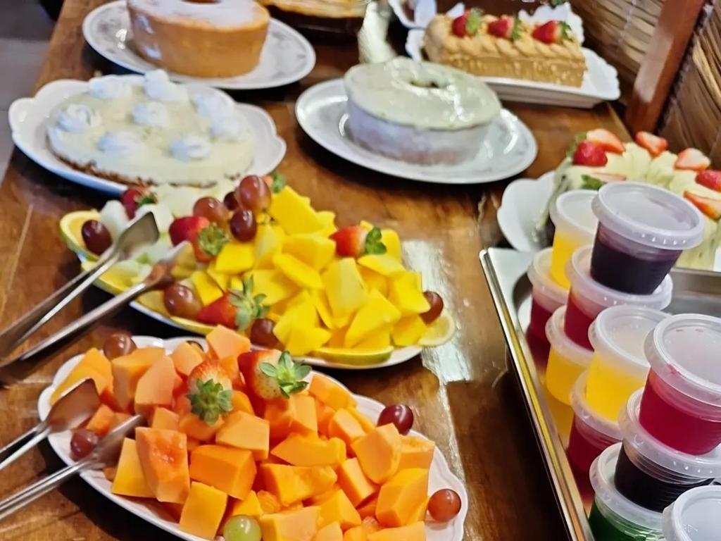 a table topped with plates of fruit and cakes at NAVEGA HOUSE in Navegantes