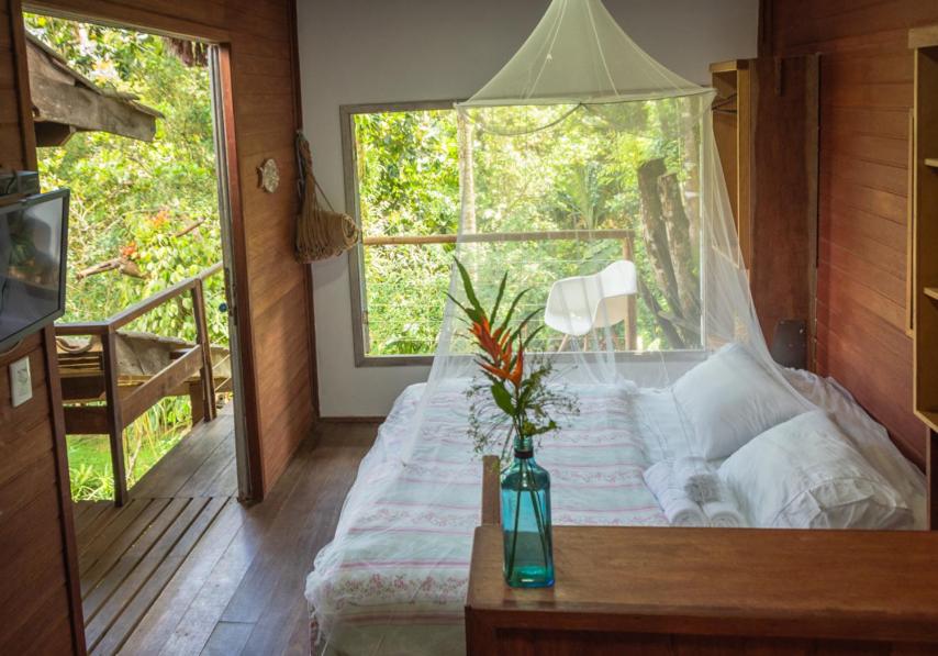 Cette chambre comprend un lit avec un vase sur une table. dans l'établissement Casa Grande Flats, à Abraão