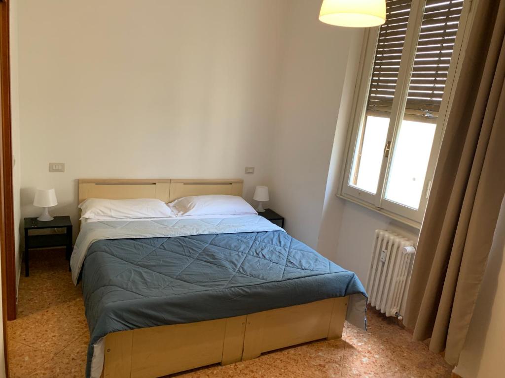 1 dormitorio con 1 cama con edredón azul y ventana en Daniele rooms en Arezzo