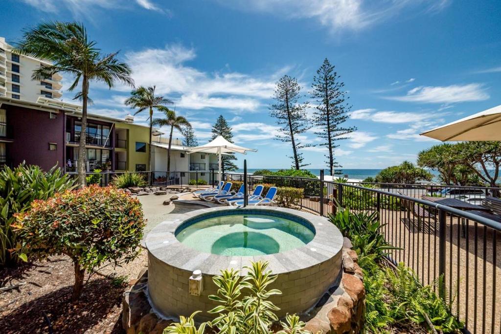 an outdoor swimming pool with chairs and an umbrella at Hear the Sea 2 mins from Coolum beach and shops in Coolum Beach