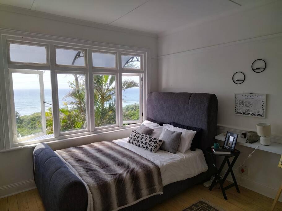 a bedroom with a bed with two windows at Sunrise beach house in Kingsburgh