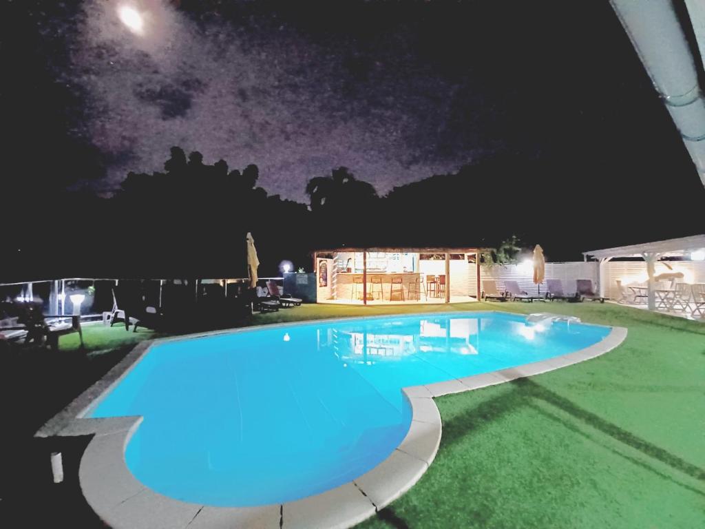 a swimming pool at night with the moon in the sky at La Rose du Bresil Marie-Galante in Capesterre